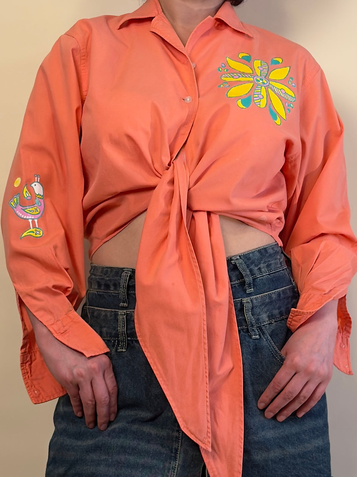 Detail view of Songbird Bloom by HANDLURIA, showing the tied front and hand-painted flower and sleeve bird motifs.
