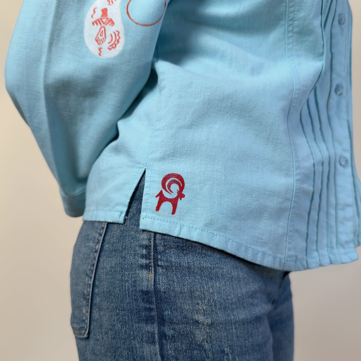 Detail view of Before Borders | Under One Sun by HANDLURIA, showing the side slit and red motif at the hem.