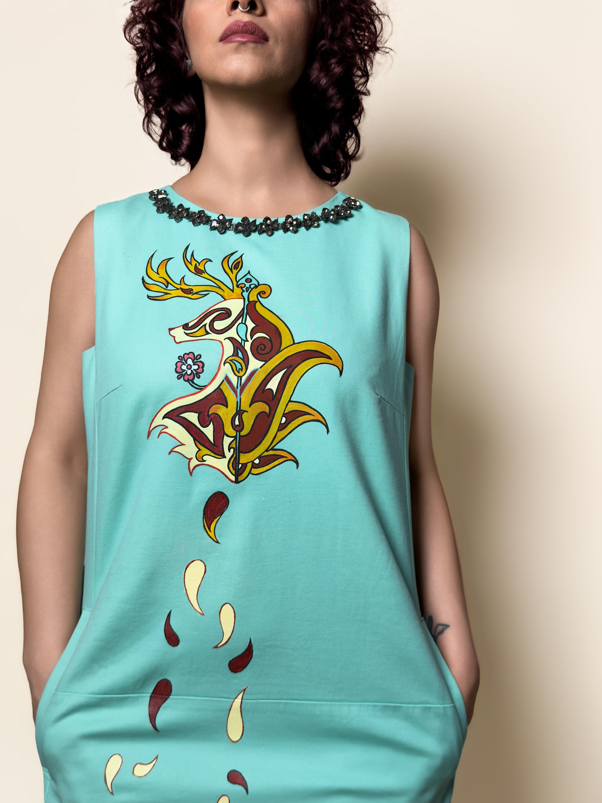Detail view of the Fireborne Stag turquoise dress by HANDLURIA, showing the hand-painted composition and decorative neckline.