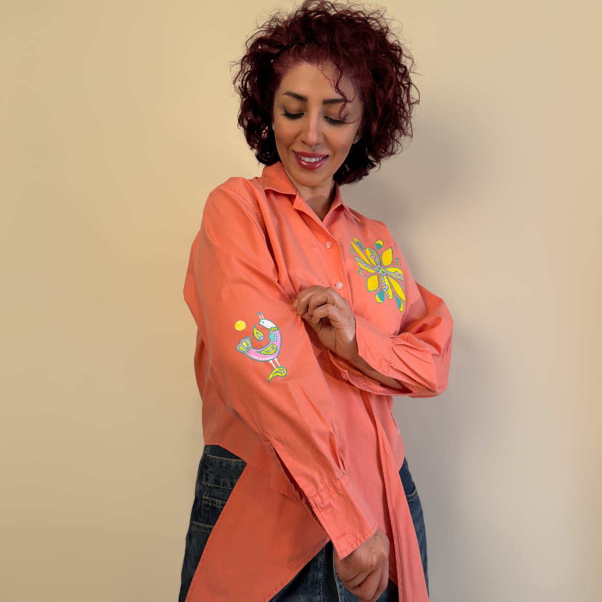 Detail view of Songbird Bloom by HANDLURIA, showing the hand-painted bird on the sleeve and flower motif on the chest.